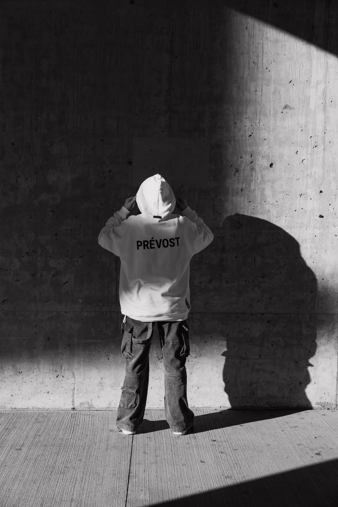 Women standing in front of concrete wall wearing a white hoodie