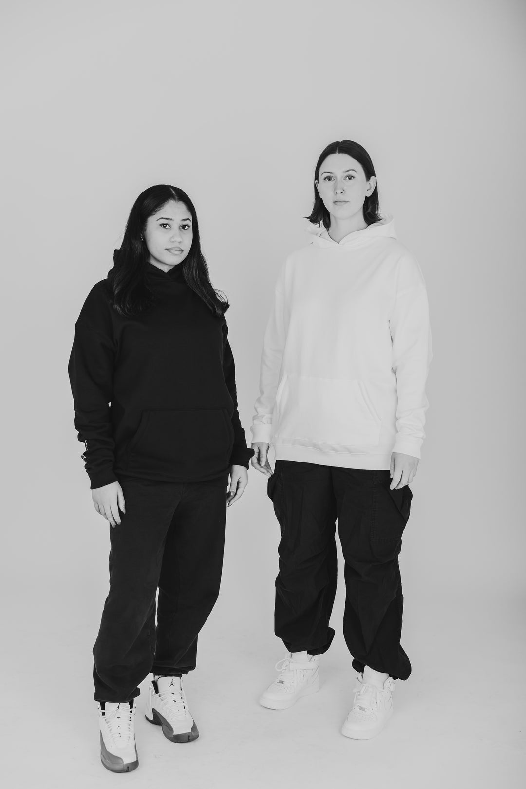 Two women wearing black and white hoodie with streetwear outfits